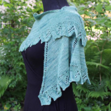 Assymetric triangular shawl has leaf pattern along bottom edge. Each leaf has pearl beads down the center.