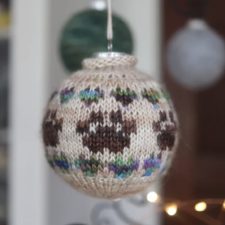 Holiday ornament with colorwork dogs paw and tiny hearts as repeating motifs.