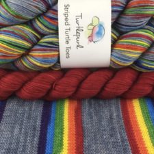Neutral yarn in a wide stripe, followed by thinner stripes in rainbow colors.