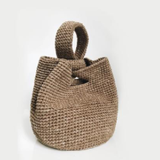 Bucket bag with a strap on one side that passes through a slot on the other side.