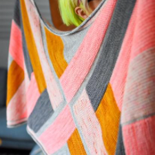 Travel Mode is a graphic rectangular shawl with a seamless modular construction that creates a herringbone pattern mirrored along a center panel.