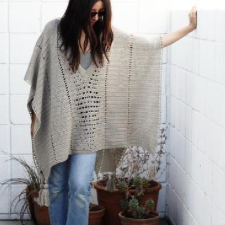 Rectangular crochet poncho with V-neck. Each corner has a 3-inch tassel.