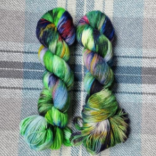 Sparkle variegated yarn in greens, with touches of deep red and deep blue.