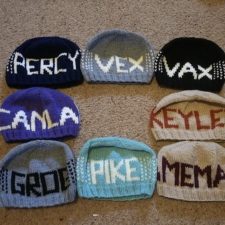 Beanies with colorwork words Vex, Vax, Keyleth, Pike, Game Master, Scanlan, Grog, and Percy.