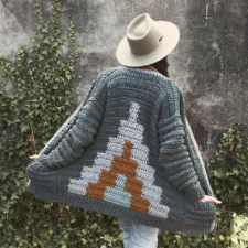 Chunky crochet cardigan with external pockets, multiple colors around the button band, and a colorwork mountain shape on the back.