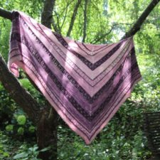 Top-down triangular shawl in monochromatic violet stripes.