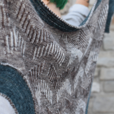 Brioche Mosaic Arrows adorn this deep triangular shawl that is surrounded by a contrasting border and an i-cord for a finished look.