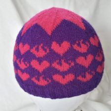 Beanie with alternating hearts and flames in colorwork. Crown has a multipointed star across the top of the hat.