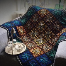 Tiled mosaic crochet blanket. Edge squares are deepest blue and green. Center squares are shades of gold from light to dark.