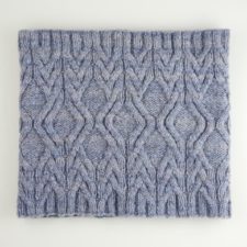 Cabled cowl with repeating vertical section of angled lines.