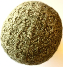Beanie divided into four segments by two-stitch stockinette vertical lines. between those lines, the beanie is solidly cabled.