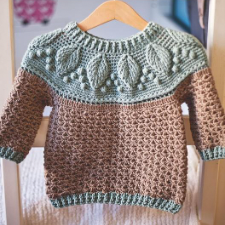 Child’s pullover with leaf texture around yoke, which is in complementary color to the body and sleeves. Cuffs and hem match yoke.