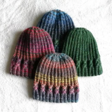 Four beanies in different colorways. Beanies are ribbed, with a simple cable about an inch above the bottom edge.