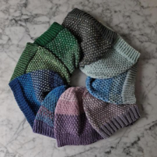 Stack of beanies in two colors or more each. Colorwork alternates the colors every other stitch.