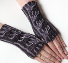 Twisting cabled fingerless mitts in two colors.