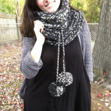 Chunky knitted cowl with drawstring at the mid point. Drawstring ends in pompoms.