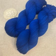 Skein in deepest blue, photographed with sand dollar.