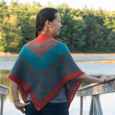 Triangular colorwork shawl with v-shaped sections in geometric patterns.