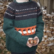 Child’s sweater in four colors with colorwork band of sheep motifs around waist.
