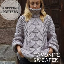 Chunky sweater mostly in garter stitch with cable about 7 inches wide down the front. Sweater has loose sleeves and a high collar.