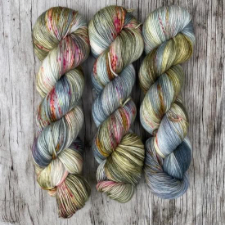 Three variegated skeins in mossy colors with hints of blue sky.