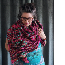 An asymmetrical triangle shawl knit using two-color brioche, speckled with bobbles created using assigned pooling.