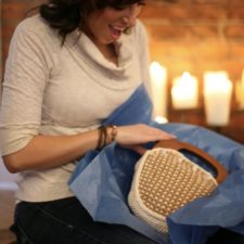 Woman opens gift of checked handbag with wood handles and button-on covers.