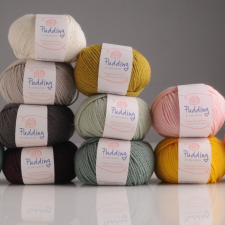 Stacks of machine-made balls of yarn in light colors and dark neutrals.