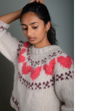 Teen wears bulky pullover with three-quarter length sleeves. Yoke has large colorwork hearts, with X’s above and below.