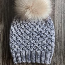 Beanie with waffle texture and large faux fur pom-pom.