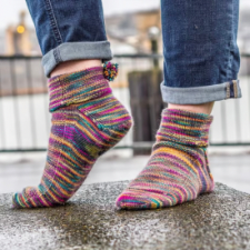 Short reverse stockinette socks with tiny sprightly pom pom at the back cuff.