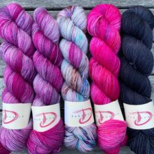Five skeins in bright colorways, three variegated and two semisolid in fuchsias and blues.