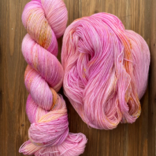 Variegated yarn that is mainly a medium pink with splashes of orange sherbet.