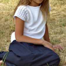 Child of 7 or 8 wears short-sleeve top. Sleeves have openwork in them.