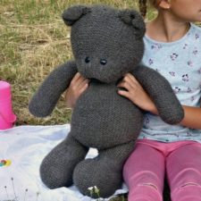 Small child holds 25 inch tall knitted bear