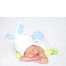 Baby sleeping while wearing a hat with bunny ears and a diaper cover with a large pompom.