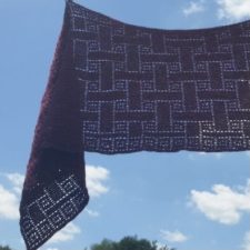 Shawl with basketweave crochet interspersed with lace, against a sunny sky.
