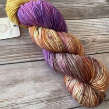 Variegated yarn that is half mixed warm tones and half warm purple.