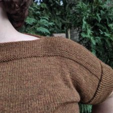 Short-sleeve stockinette top with garter stitch accents across shoulders and at edges.