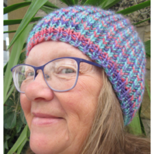 Sue Beard, smiling in colorful, ribbed beanie.