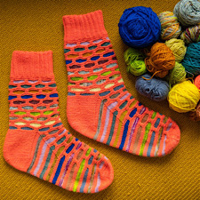 Colorwork socks with solid color laid out like mortar in brickwork, then scraps or gradient yarn as the “bricks” background.
