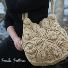 Highly textured shoulder bag with leave motifs. Crocheted straps attached near large bobbles that look like buttons.