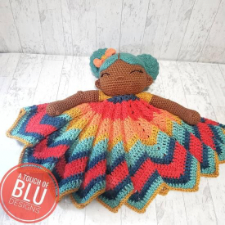 Crocheted cuddler in the form of a little girl with aqua Afropuffs and a full, multicolor skirt.