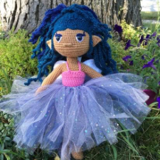 Doll in knitted leotard with tulle tutu. She has blue, sparkly hair in a braided style.