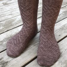 Socks with traveling cables that form the overlapping rectangles of brickwork.