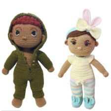 A boy doll in hoodie pajamas and a girl in a onesie and legwarmers. The girl has a headband with a bow and bunny ears.