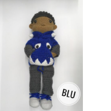 Boy doll with hands shoved into the pockets of a sweater with a monster’s teeth and eyes in colorwork.