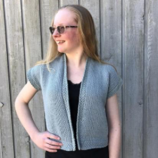 Teen wears short-sleeve open front simple stitch cardigan with honeycomb stitch at hem, button band and cuffs.
