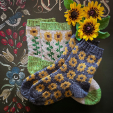 Two sock patterns. One is sunflower blooms on a dark background. The other is sunflowers on long stems down the leg of the socks.