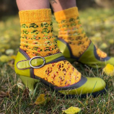 Topdown, stranded colorwork socks that almost resemble a leopard print, shown in bright strappy retro shoe.